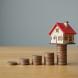 Une maison miniature posée en équilibre sur des pièces de monnaie