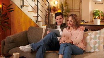 Un couple regarde une tablette ensemble sur un canapé 