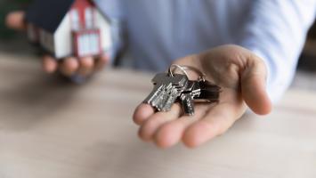 Agent immobilier tenant des clés et une maquette de maison