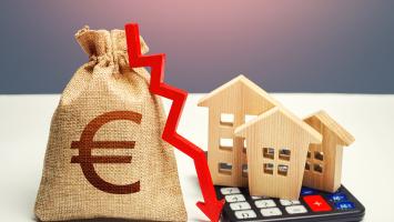 Un sac d'argent avec un symbole euro, une flèche rouge pointant vers le bas, des maisons en bois et une calculatrice, symbolisant la diminution de la valeur immobilière.