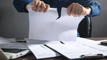  Une personne déchire un document au-dessus d'un bureau encombré