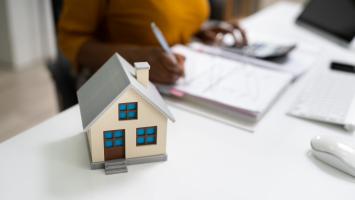 petite maisonnette posé sur le bureau avec une signature de contrat