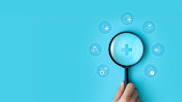 Une main avec une loupe qui examine des pictogrammes santé