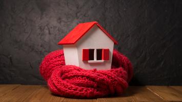 Une maison miniature entourée d'une écharpe en laine rouge