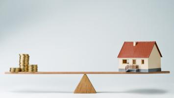 Maison miniature en équilibre sur une planche en bois