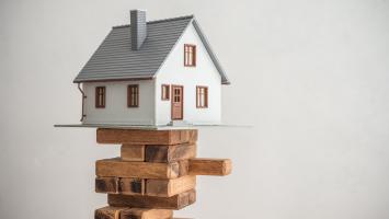 Une maison miniature en équilibre sur un édifice en bois
