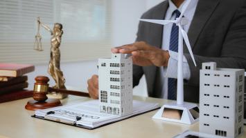 Bureau avec immeuble miniature, balance de droit et marteau