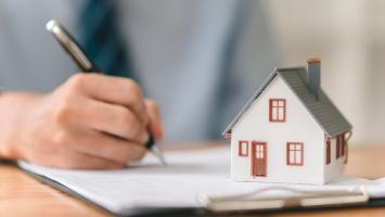 Modèle maison, stylo et bloc-notes sur la table, marché immobilier, négociation d'investissement