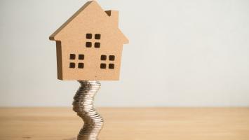 Une maison en équilibre sur une pile de pièces de monnaie
