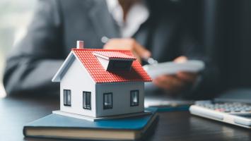 Une maquette de maison posée sur le bureau d'un professionnel de l'immobilier