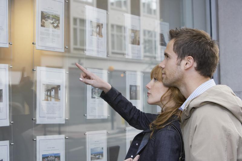 couple devant une vitrine d'annonces immobilières