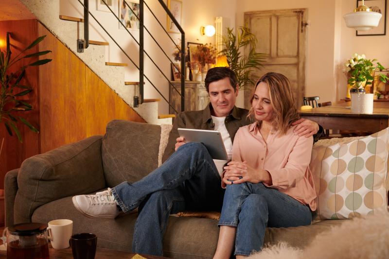 Un couple regarde une tablette ensemble sur un canapé 