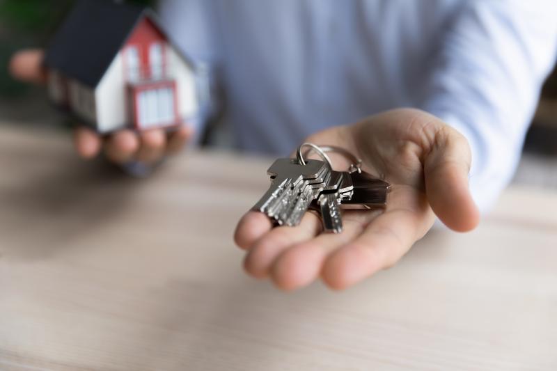 Agent immobilier tenant des clés et une maquette de maison