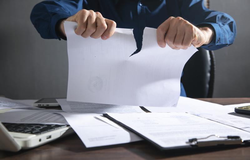  Une personne déchire un document au-dessus d'un bureau encombré