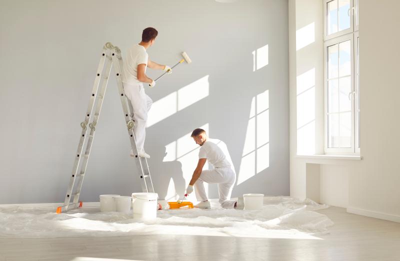 Équipe de peintres professionnels en vêtements blancs peignant un mur