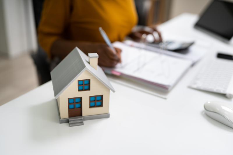 petite maisonnette posé sur le bureau avec une signature de contrat