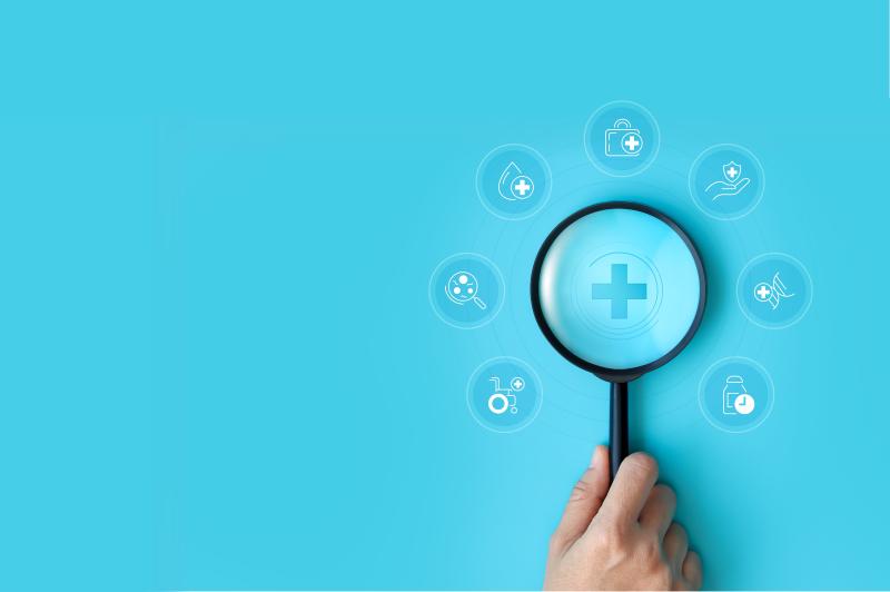 Une main avec une loupe qui examine des pictogrammes santé