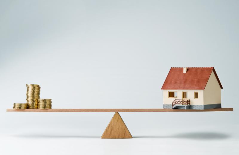 Maison miniature en équilibre sur une planche en bois