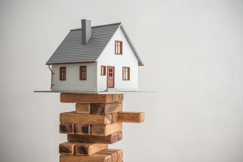 Une maison miniature en équilibre sur un édifice en bois