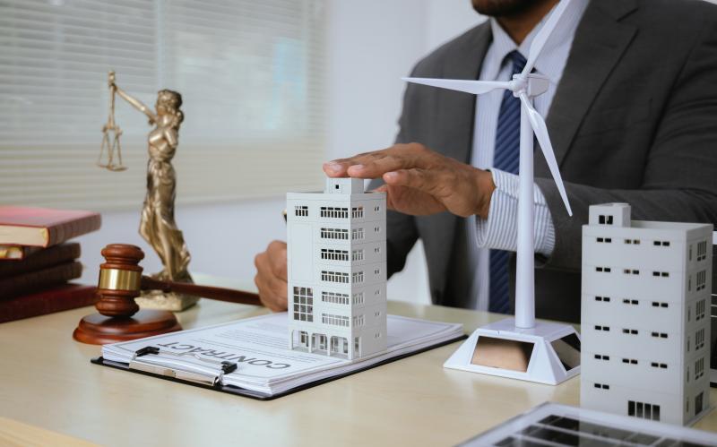 Bureau avec immeuble miniature, balance de droit et marteau