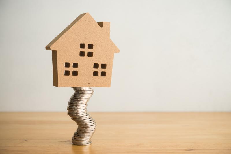 Une maison en équilibre sur une pile de pièces de monnaie