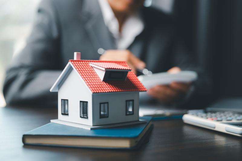 Une maquette de maison posée sur le bureau d'un professionnel de l'immobilier